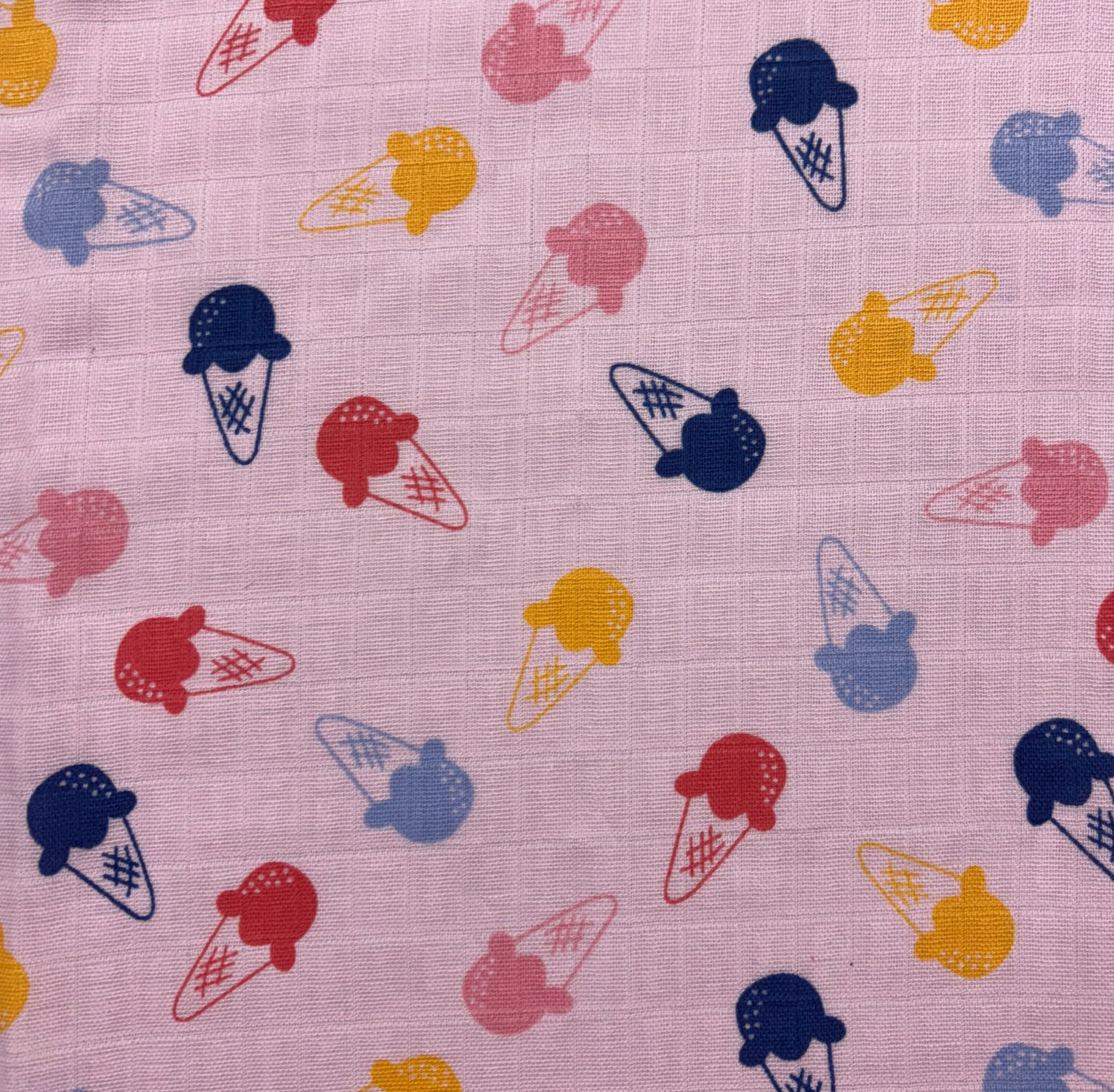 A vibrant roll of printed muslin fabric being unrolled to reveal its colorful patterns designed for summer fashion.