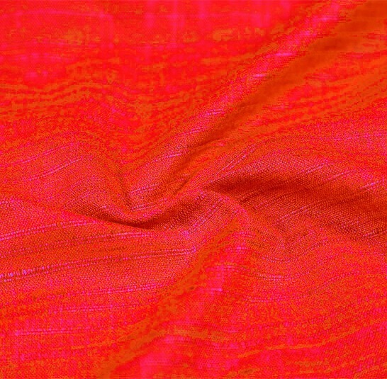 A close-up of crushed muslin fabric draped elegantly, highlighting its textured surface and vibrant colors.